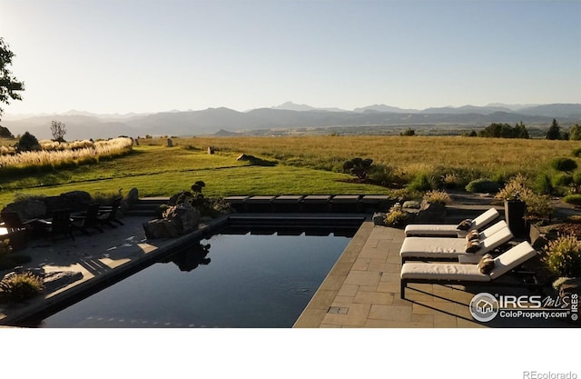 view of swimming pool with a rural view, a mountain view, and a patio