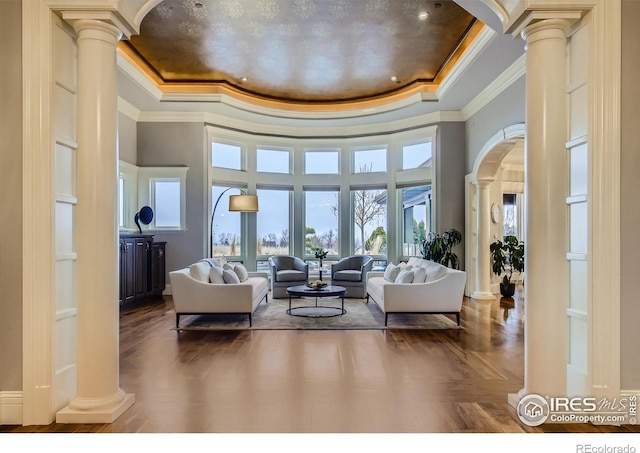 living room with a tray ceiling, crown molding, and ornate columns