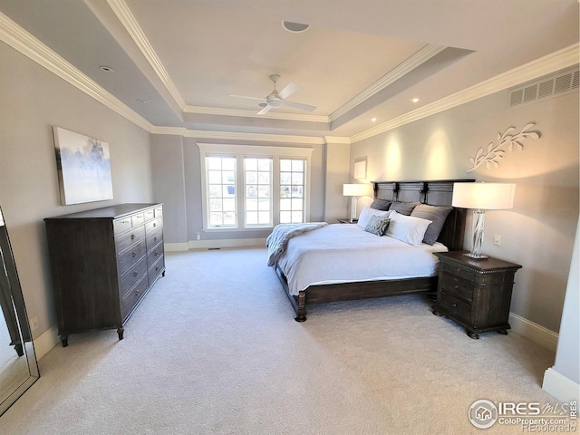 bedroom with ceiling fan, light carpet, a tray ceiling, and ornamental molding