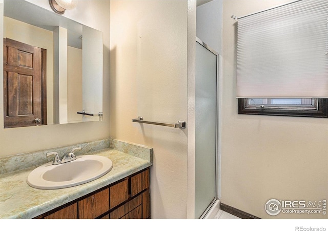 bathroom with a shower with door and vanity