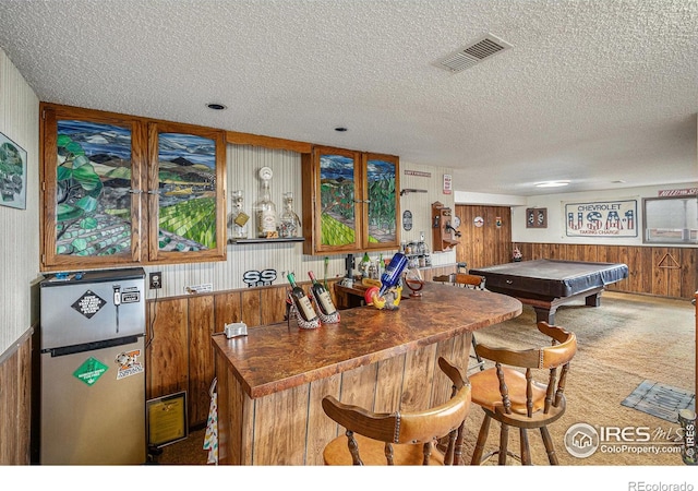 kitchen with pool table, carpet flooring, a kitchen breakfast bar, a textured ceiling, and stainless steel refrigerator