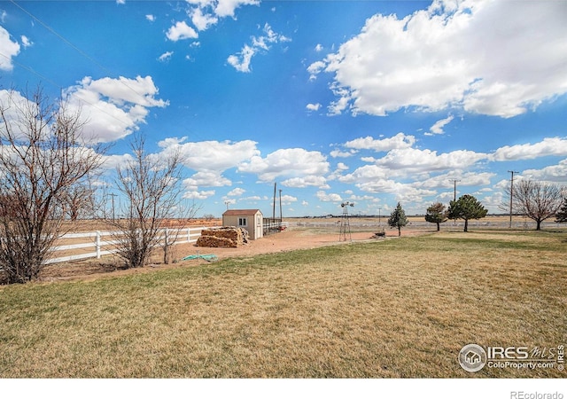 view of yard featuring a rural view and a shed