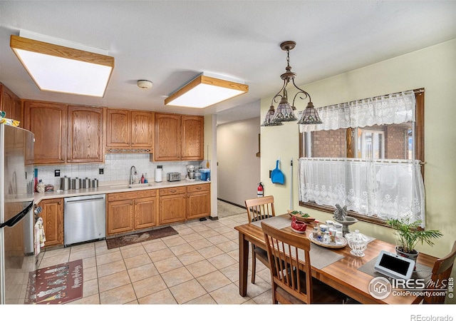 kitchen featuring appliances with stainless steel finishes, pendant lighting, tasteful backsplash, light tile floors, and sink