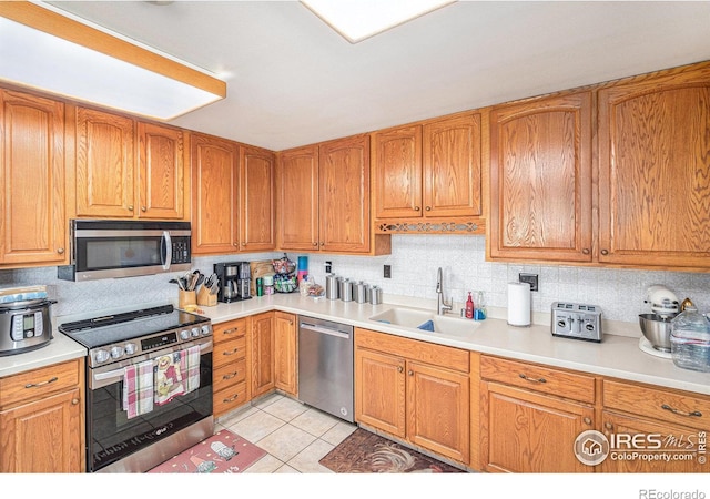 kitchen featuring tasteful backsplash, appliances with stainless steel finishes, light tile floors, and sink