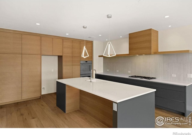 kitchen with a kitchen island with sink, sink, and hanging light fixtures