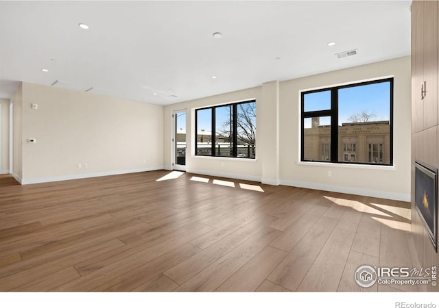 unfurnished living room with a large fireplace and light wood-type flooring