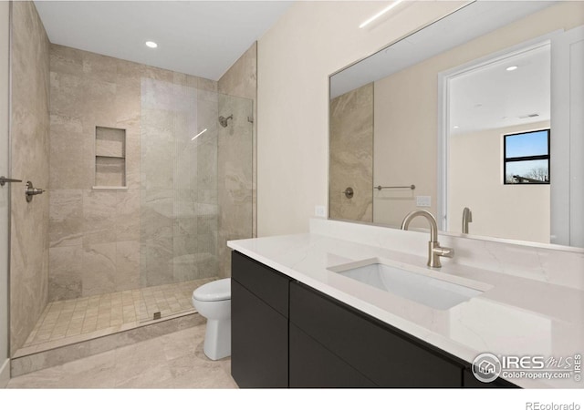 bathroom featuring tiled shower, vanity, and toilet