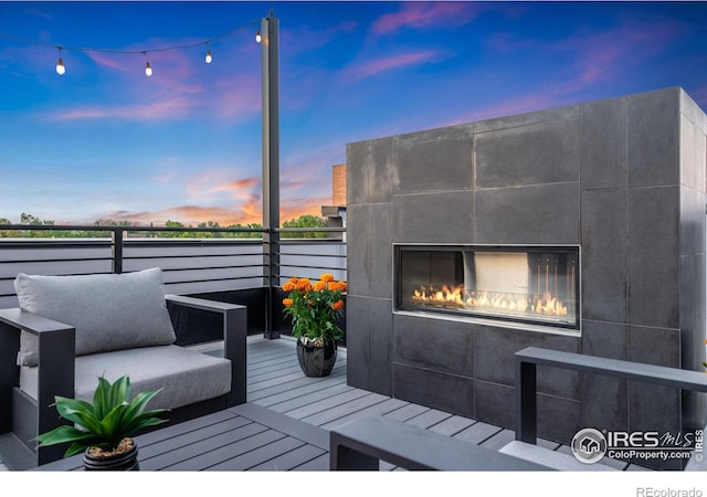 deck at dusk featuring an outdoor living space with a fireplace