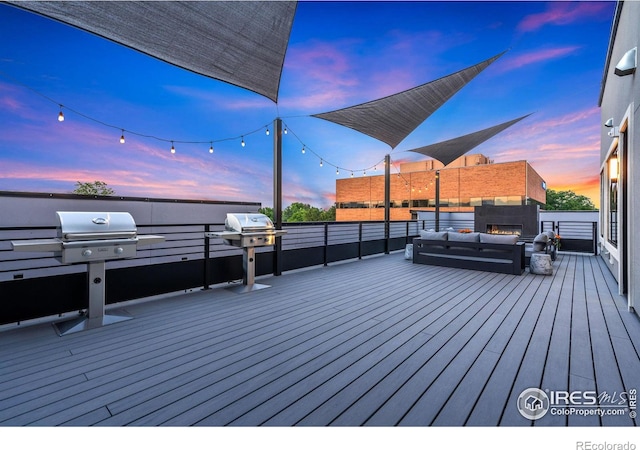 deck at dusk featuring outdoor lounge area and a grill