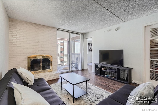 living room with a textured ceiling, a brick fireplace, and dark hardwood / wood-style floors