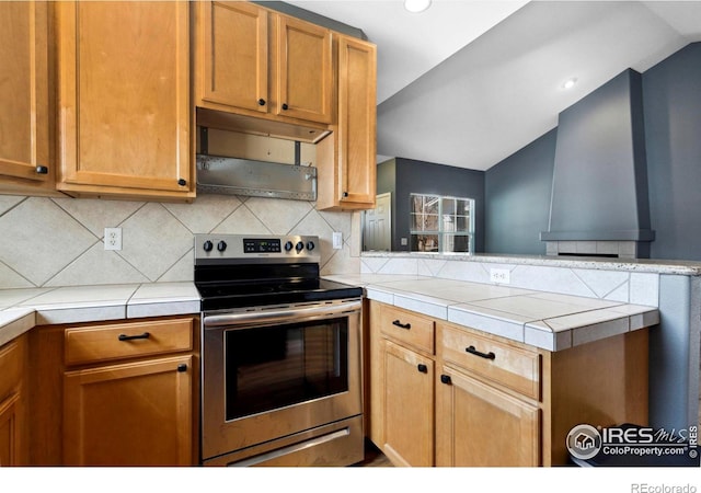 kitchen with backsplash, tile counters, stainless steel electric range, and kitchen peninsula