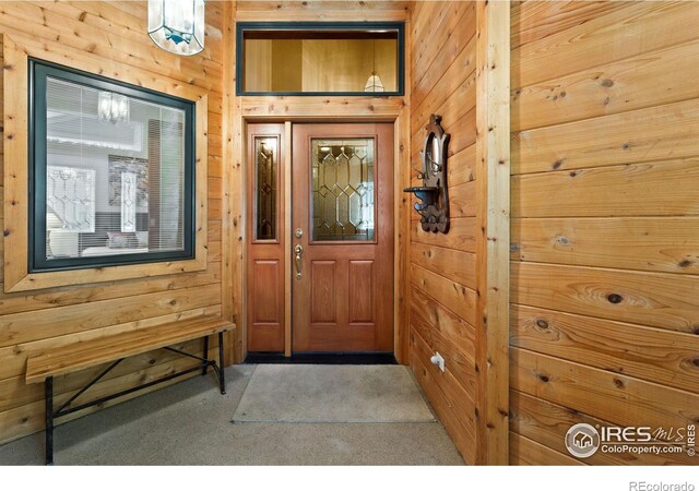 entrance foyer with wood walls and carpet floors