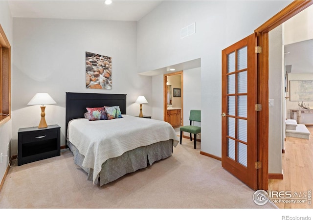 bedroom with light colored carpet, connected bathroom, and a high ceiling