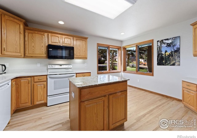 kitchen with a kitchen island, white appliances, light hardwood / wood-style flooring, and light stone countertops