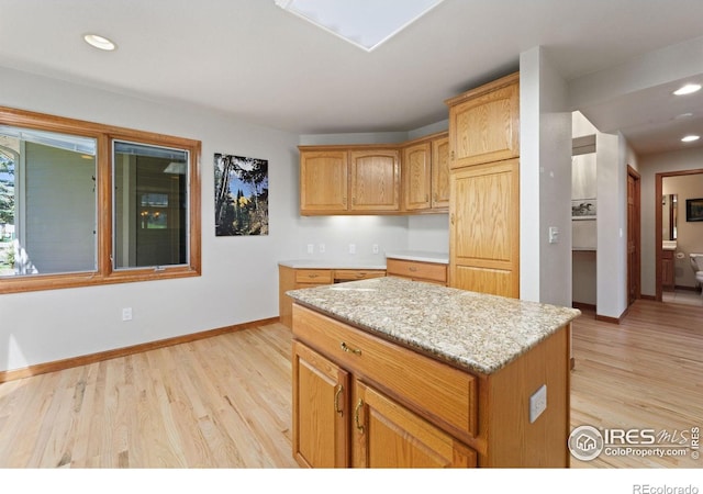 kitchen featuring light hardwood / wood-style flooring, a center island, and light stone countertops