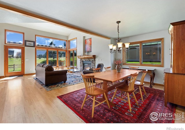 dining area with a notable chandelier, light hardwood / wood-style flooring, and a stone fireplace