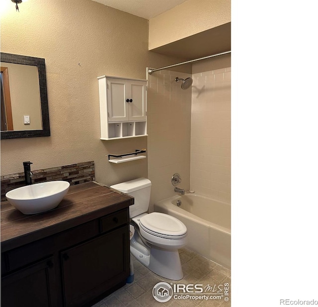 full bathroom with tile floors, tiled shower / bath combo, vanity, and toilet