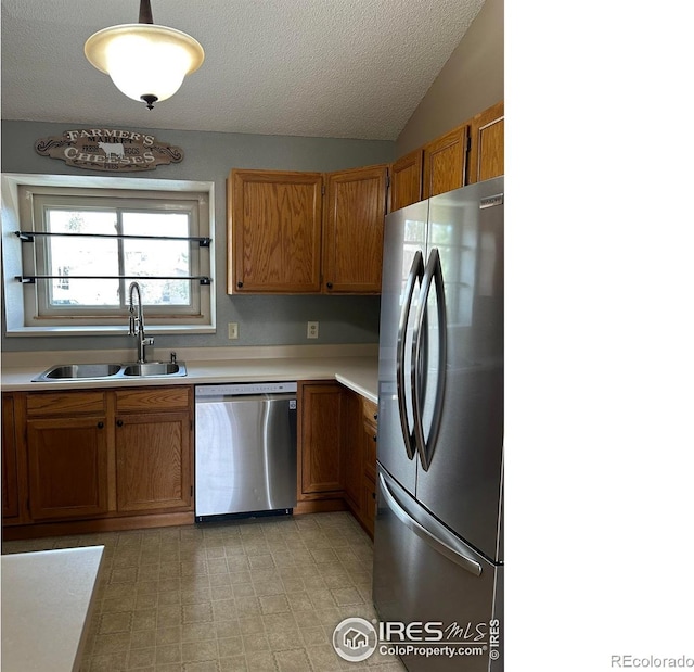 kitchen with vaulted ceiling, light tile floors, hanging light fixtures, sink, and appliances with stainless steel finishes