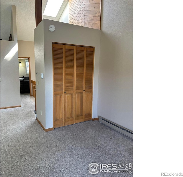 unfurnished bedroom featuring a closet, carpet flooring, a textured ceiling, a baseboard radiator, and a skylight