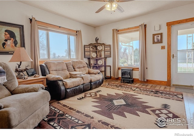 living room featuring a wood stove, ceiling fan, hardwood / wood-style floors, and a textured ceiling