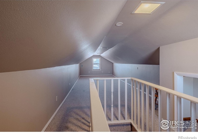 stairs with lofted ceiling, carpet, and a textured ceiling