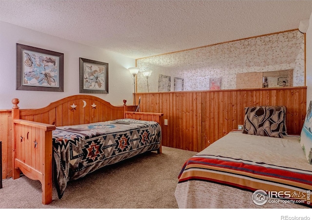 bedroom with carpet flooring, wood walls, and a textured ceiling