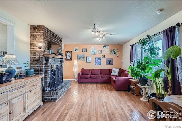 living room with a textured ceiling, a fireplace, and light hardwood / wood-style flooring