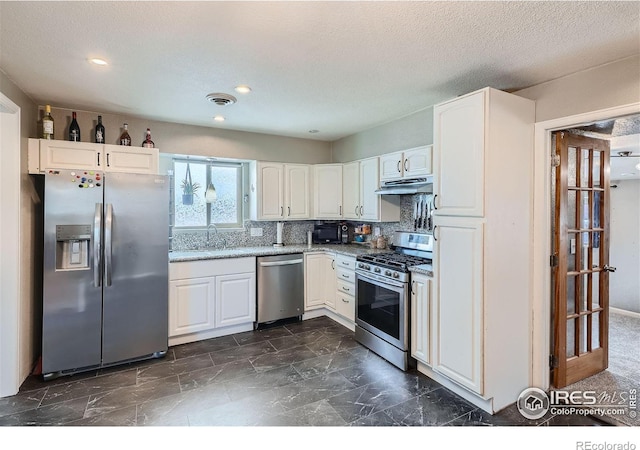 kitchen with light stone countertops, sink, stainless steel appliances, a textured ceiling, and white cabinets