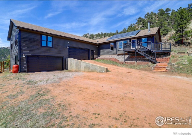 1553 Rowell Dr, Lyons, CO 80540 - view of front of home featuring dirt driveway, roof mounted solar panels, a deck, stairway, and a garage
