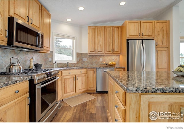 1553 Rowell Dr, Lyons, CO 80540 - kitchen featuring appliances with stainless steel finishes, crown molding, light wood finished floors, a sink, and dark stone counters