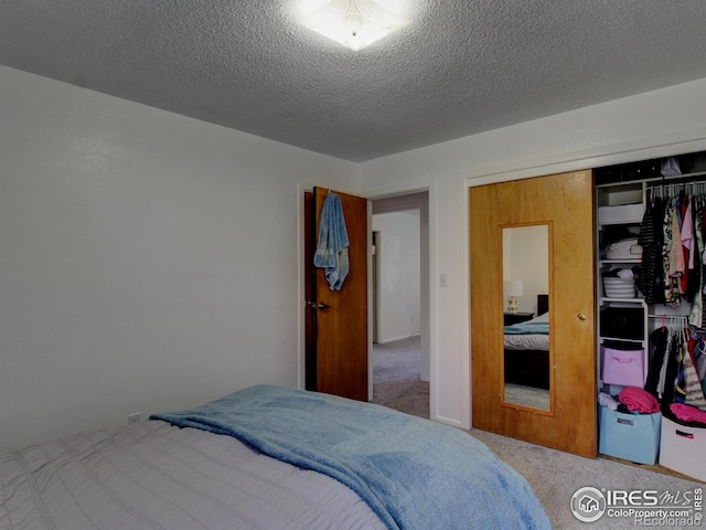 carpeted bedroom with a textured ceiling and a closet