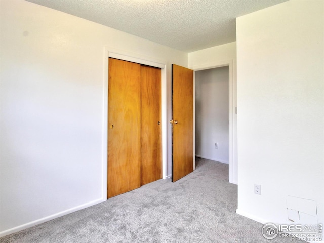 unfurnished bedroom featuring a closet, carpet flooring, and a textured ceiling