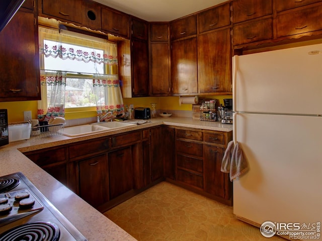 kitchen with sink, light tile patterned flooring, white refrigerator, and stainless steel stovetop