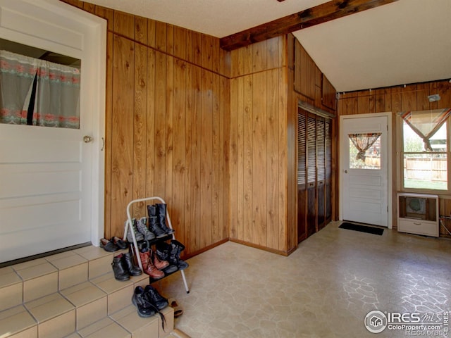 entrance foyer featuring vaulted ceiling with beams and wood walls