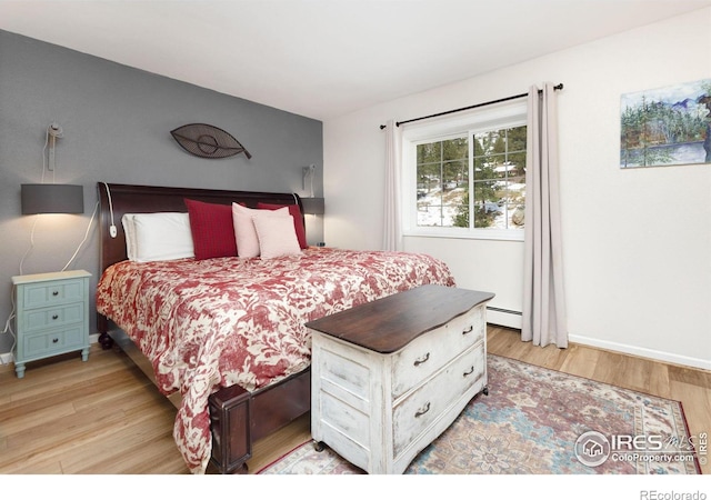 bedroom featuring a baseboard heating unit and light wood-type flooring