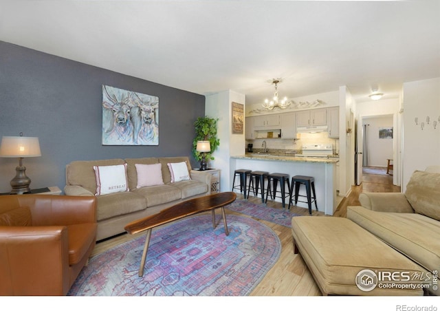 living room featuring an inviting chandelier, light hardwood / wood-style floors, and sink