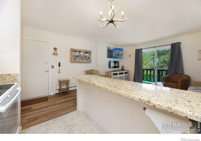 kitchen with range, light tile flooring, decorative light fixtures, baseboard heating, and light stone countertops