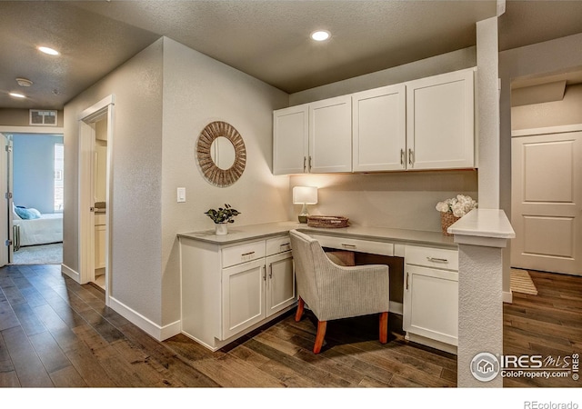 office area with dark hardwood / wood-style flooring, built in desk, and a textured ceiling