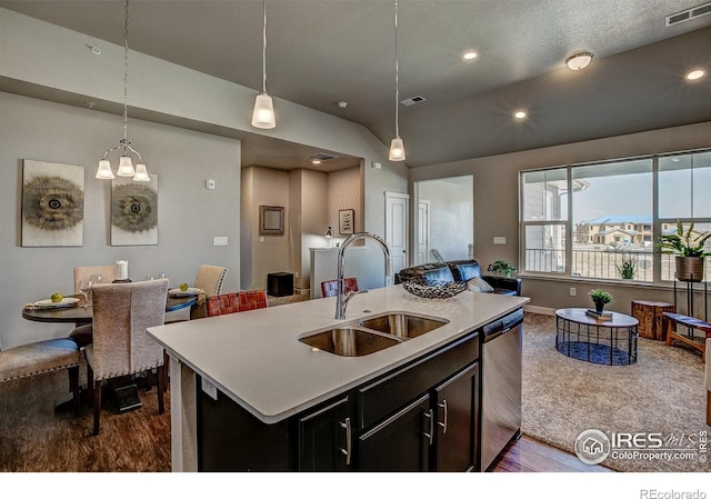 kitchen with dark hardwood / wood-style flooring, decorative light fixtures, a center island with sink, sink, and stainless steel dishwasher