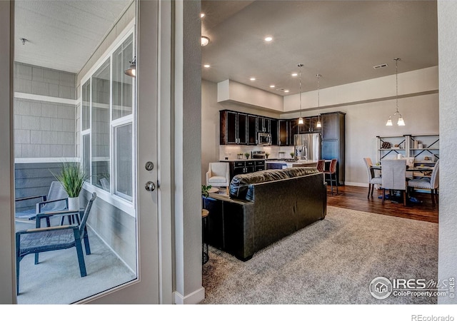 kitchen featuring wood-type flooring, a notable chandelier, stainless steel appliances, hanging light fixtures, and a center island