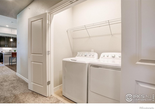 clothes washing area featuring light carpet and independent washer and dryer