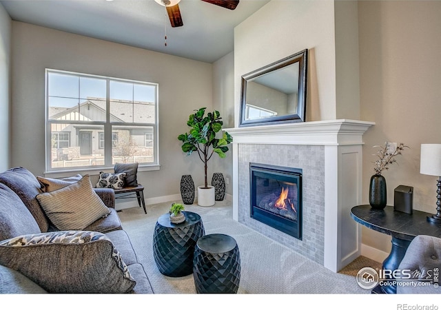 carpeted living room with ceiling fan and a tiled fireplace