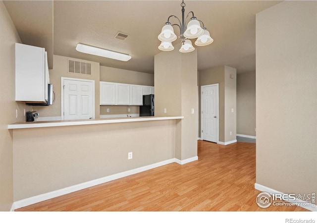 6925 19th St Unit 15, Greeley, CO 80634 - kitchen with black fridge, decorative light fixtures, light hardwood / wood-style floors, white cabinetry, and a chandelier