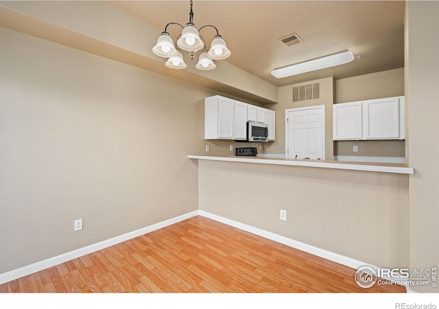 6925 19th St Unit 15, Greeley, CO 80634 - kitchen with light hardwood / wood-style floors, decorative light fixtures, white cabinets, and a notable chandelier