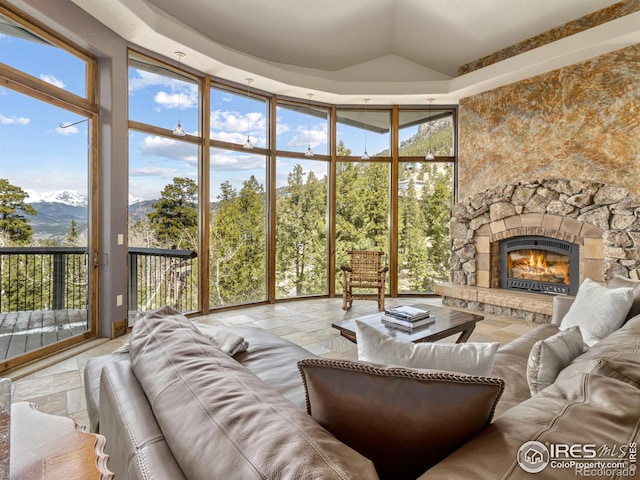 living room featuring a stone fireplace, expansive windows, and a mountain view