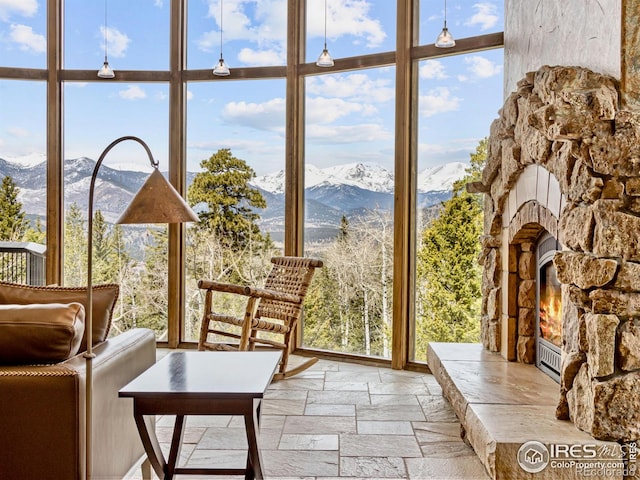 sunroom featuring a mountain view, plenty of natural light, and an outdoor stone fireplace