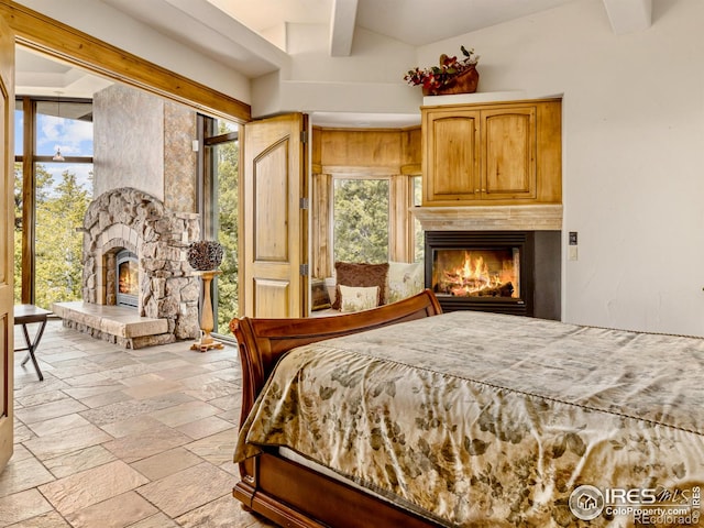 bedroom with beamed ceiling, a fireplace, and multiple windows