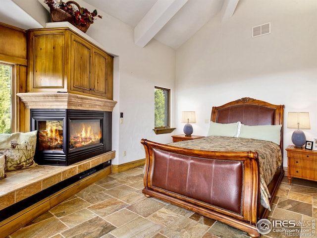 bedroom with beam ceiling, a multi sided fireplace, and high vaulted ceiling