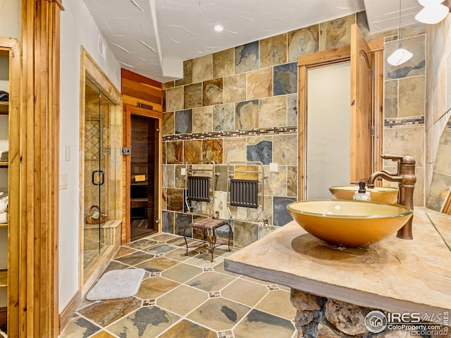 bathroom with tile walls, a shower with door, and sink