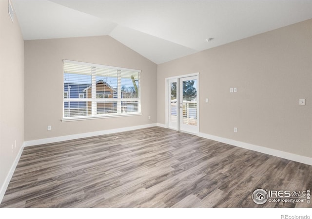 spare room featuring hardwood / wood-style flooring and lofted ceiling